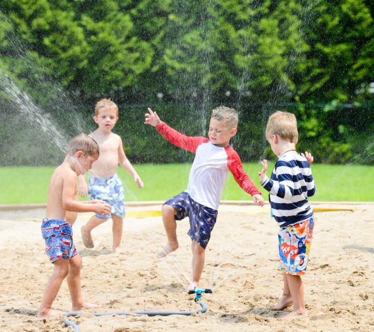 Campers playing next to sprinklers outside.