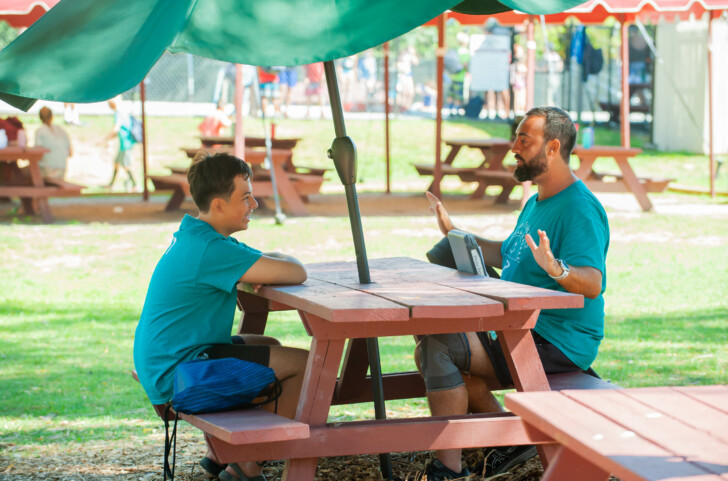 A staff member and camper sitting together.