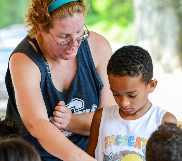 A Summer Trails staff member helping a camper.