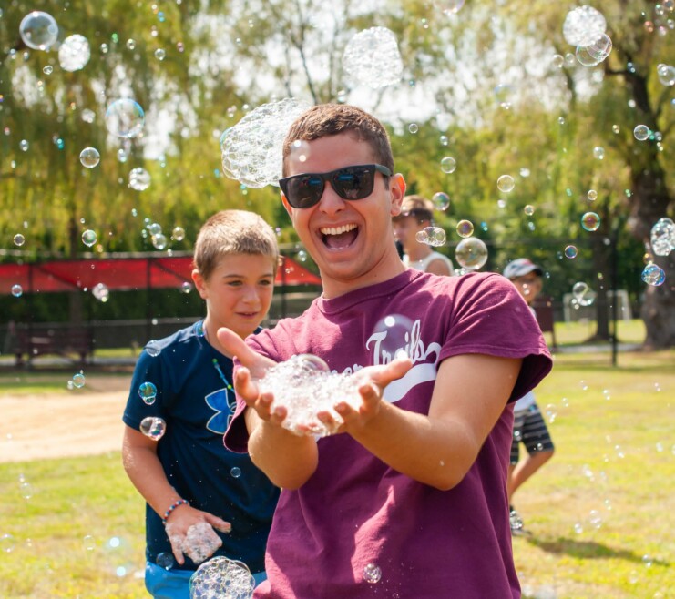 A Summer Trails staff members holding bubbles.