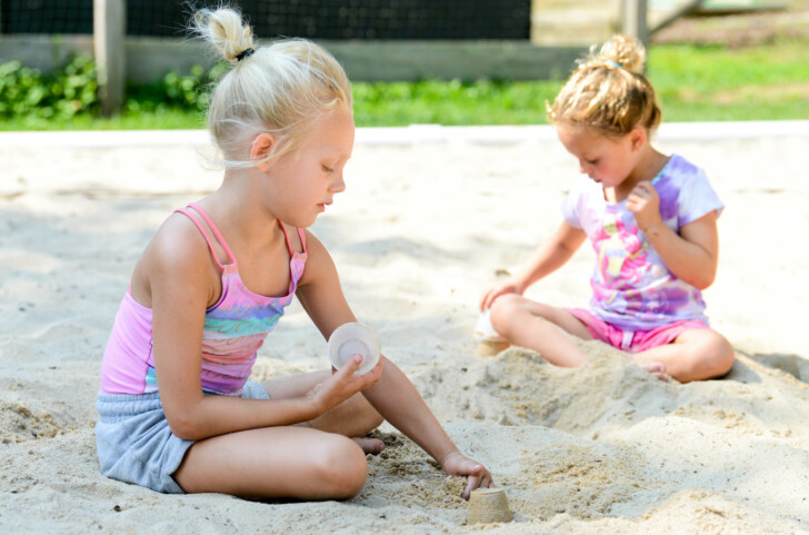 Two campers playing in a sandbox.